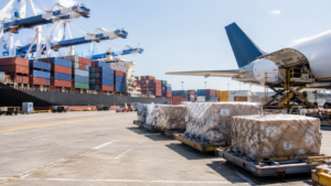 Ocean containers and air cargo pallets at a logistics hub for international freight forwarding.